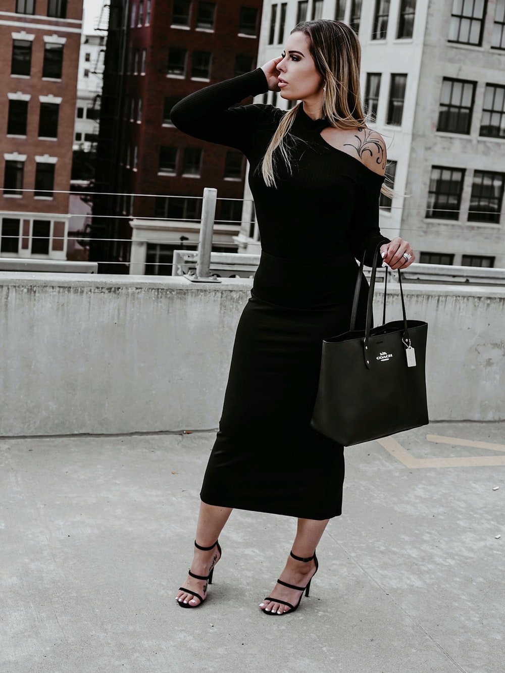 woman in black long sleeve dress holding black leather handbag