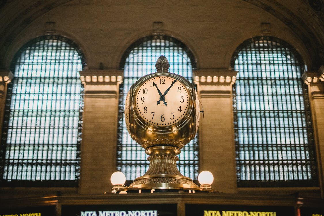 Free From below of aged retro golden clock placed atop information booth of historic Grand Central Terminal with arched windows Stock Photo